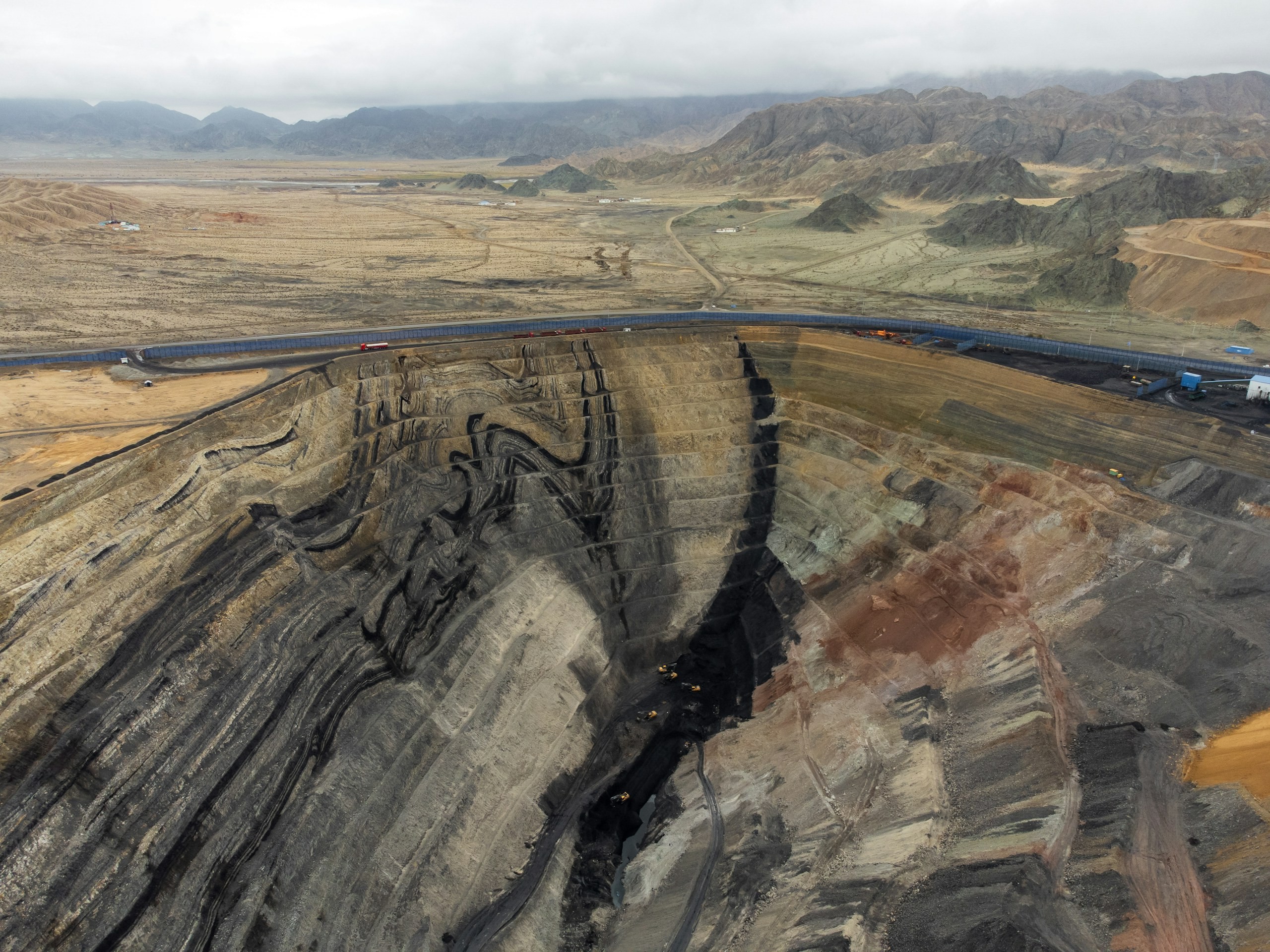 Open-pit mine with exposed rock strata and haul roads down to the pit floor