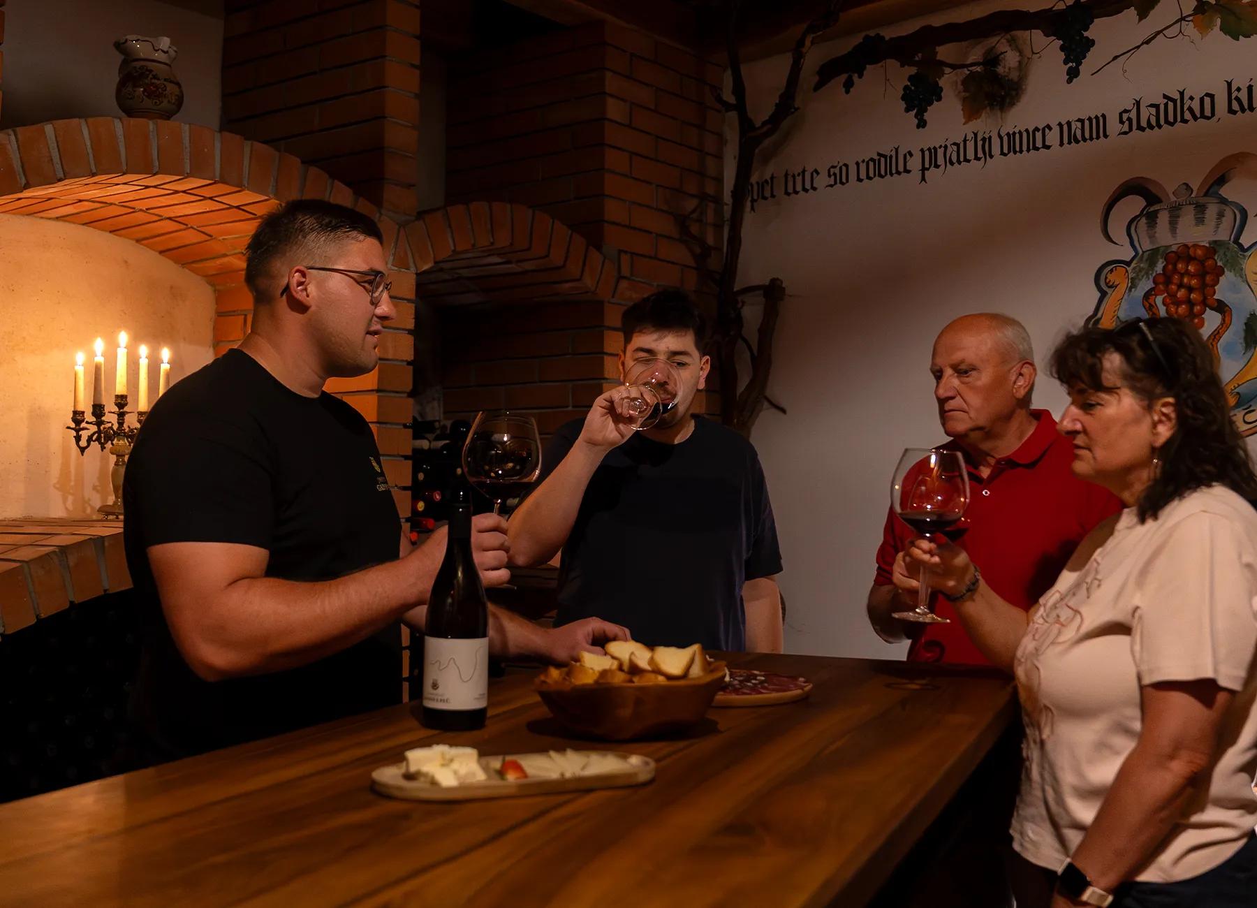 Wine tasting at a wooden table in the vaulted cellar beneath the family crest, served with bread and cheese