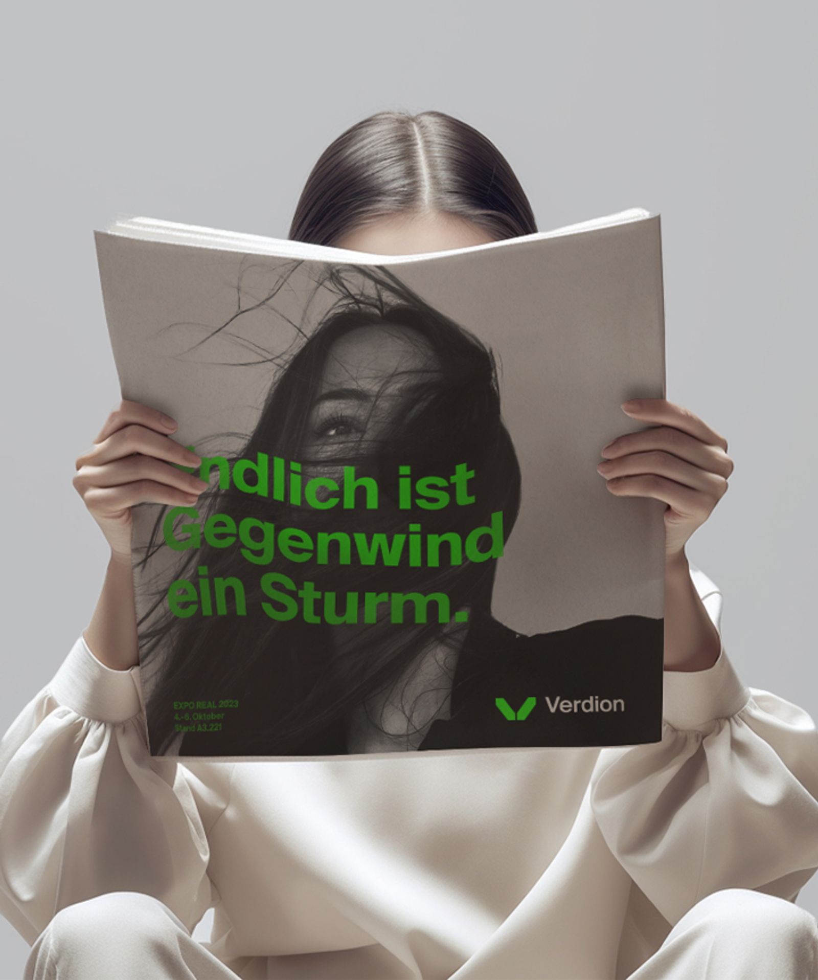 Person reading a magazine ad “Endlich ist Gegenwind ein Sturm.”