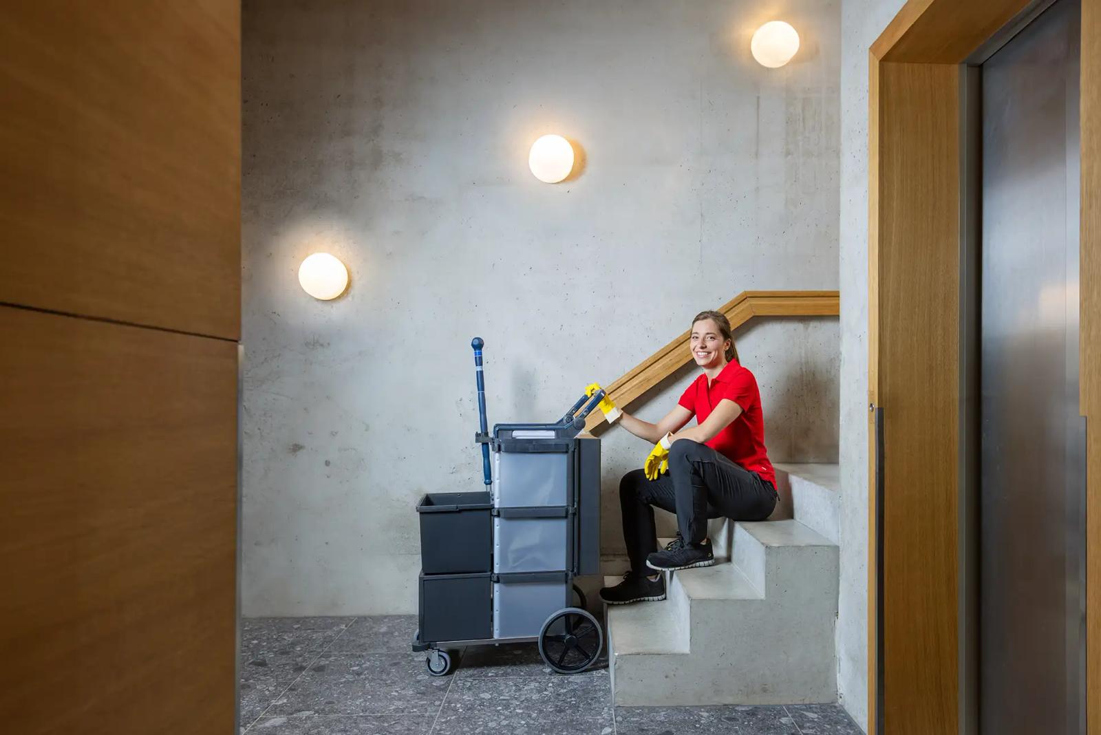 Cleaner on a stairwell landing with the Shopster trolley resting on the step