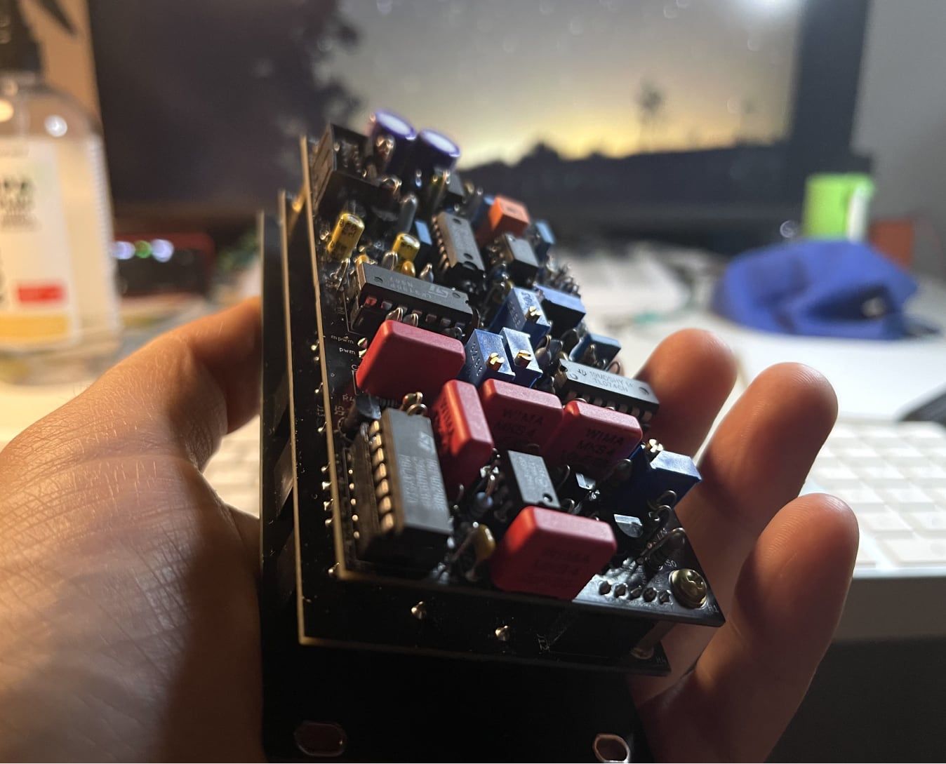 Hand holding the Re:formant circuit boards at sunset