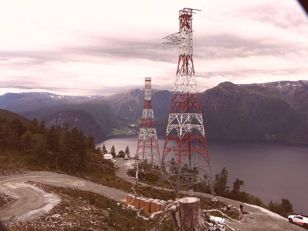 To store rød- og hvitmalte spennmaster i fjellsiden ved Sognefjorden.