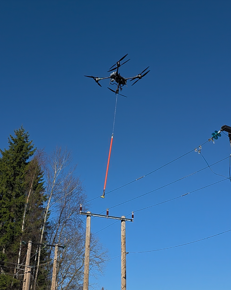 Bildet viser drone som flyr og jobber på linje ute i skogen.