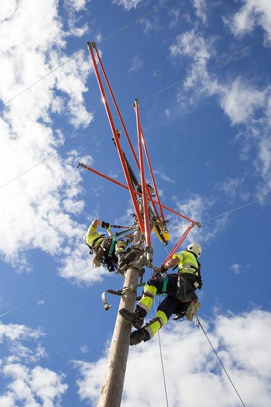 Bildet viser to menn som klatrer i en strømstolpe
