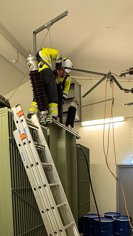Bildet viser to menn som bytter transformatorgjenomføringer