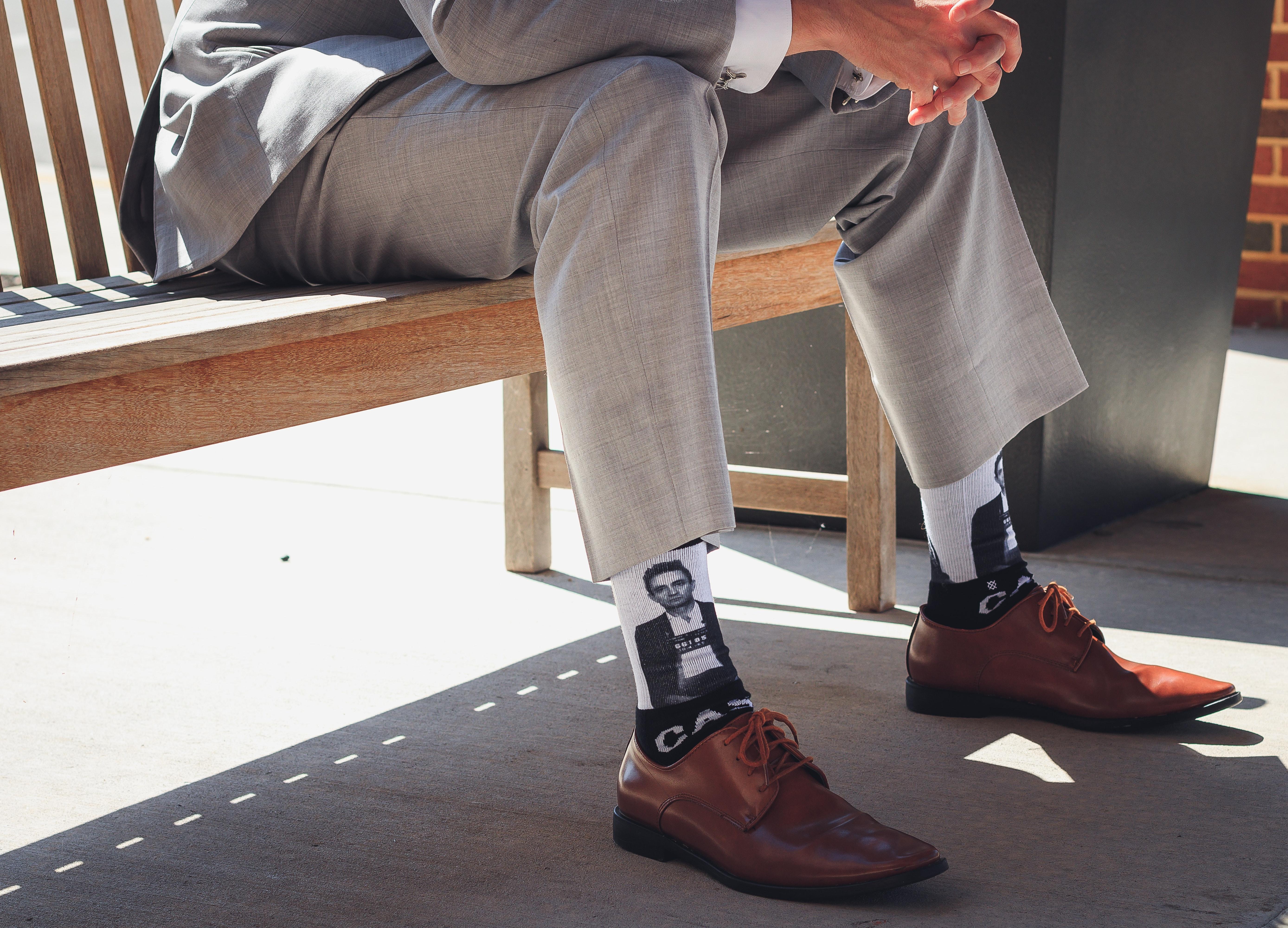 Mann mit Anzug und bedruckten Socken sitzt auf einer Bank