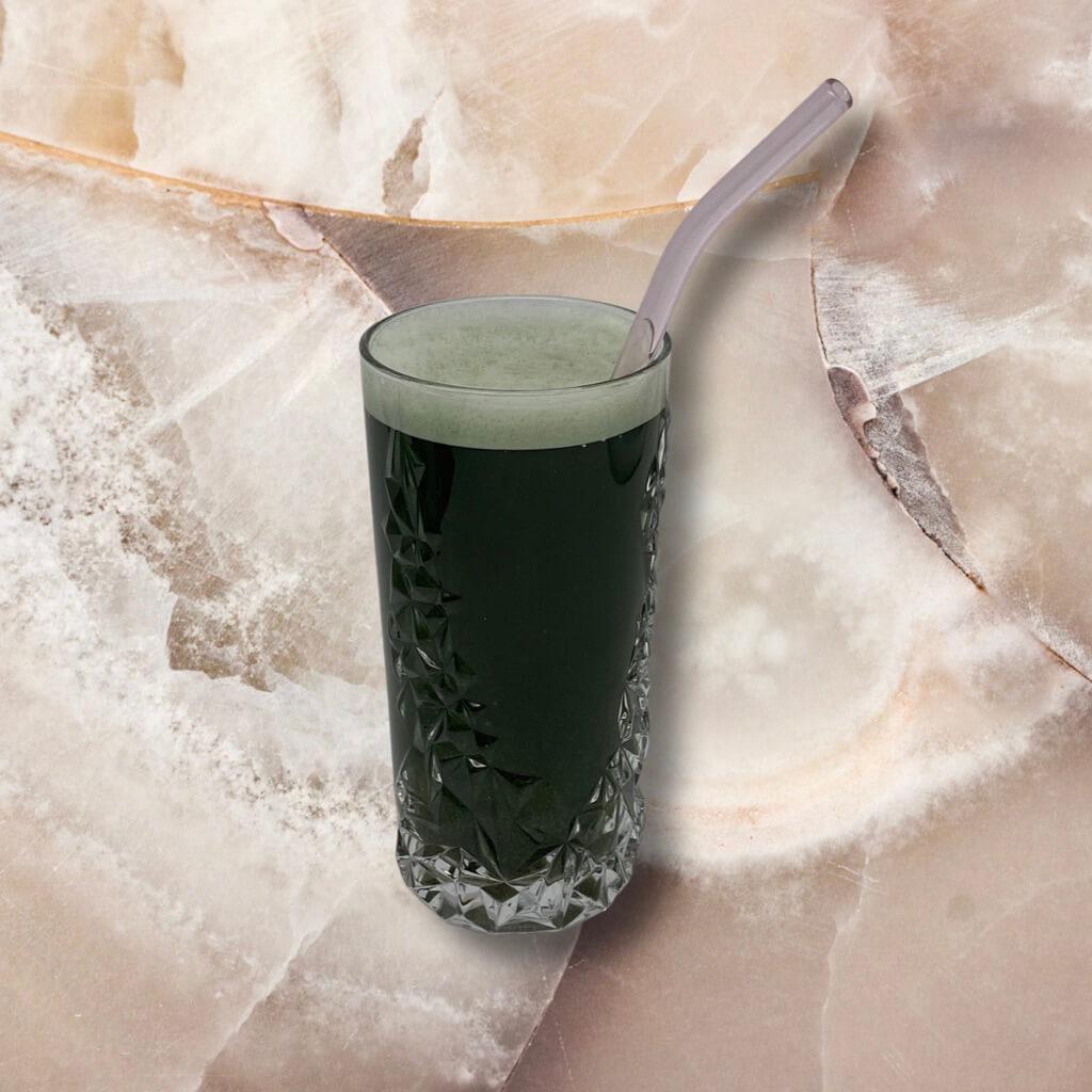 Ein großes Glas gefüllt mit grünem Athletic Greens Nahrungsergänzungsmittel und einem Strohhalm.
