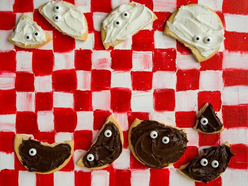 Biscuits en forme de fantômes sur nappe à carreaux rouges et blancs, vus de dessus
