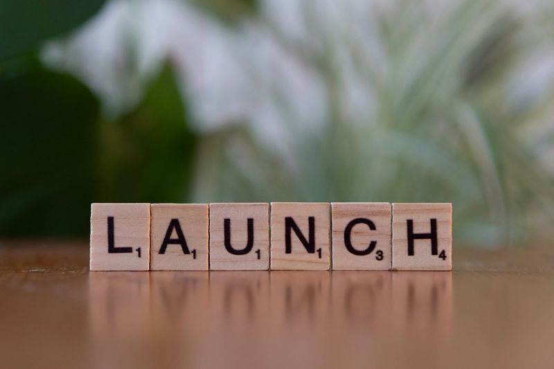 Tuiles Scrabble en bois formant le mot LAUNCH sur une surface réfléchissante