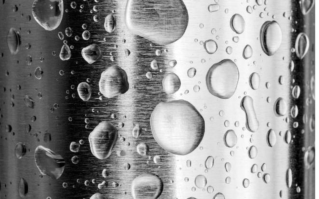 Gocce d'acqua su una superficie in acciaio inox AISI 316 Fontealta, dettaglio macro della resistenza alla salsedine