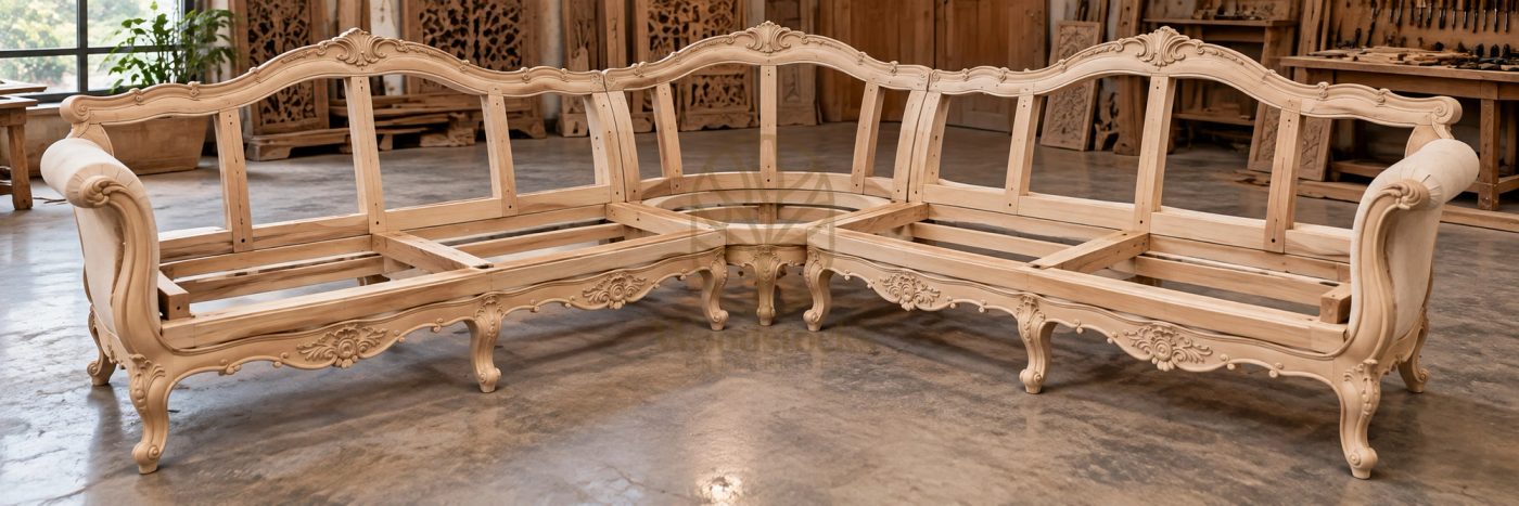 Hand carved solid wood L shape sofa frame in the workshop before upholstery, showing the corner joinery