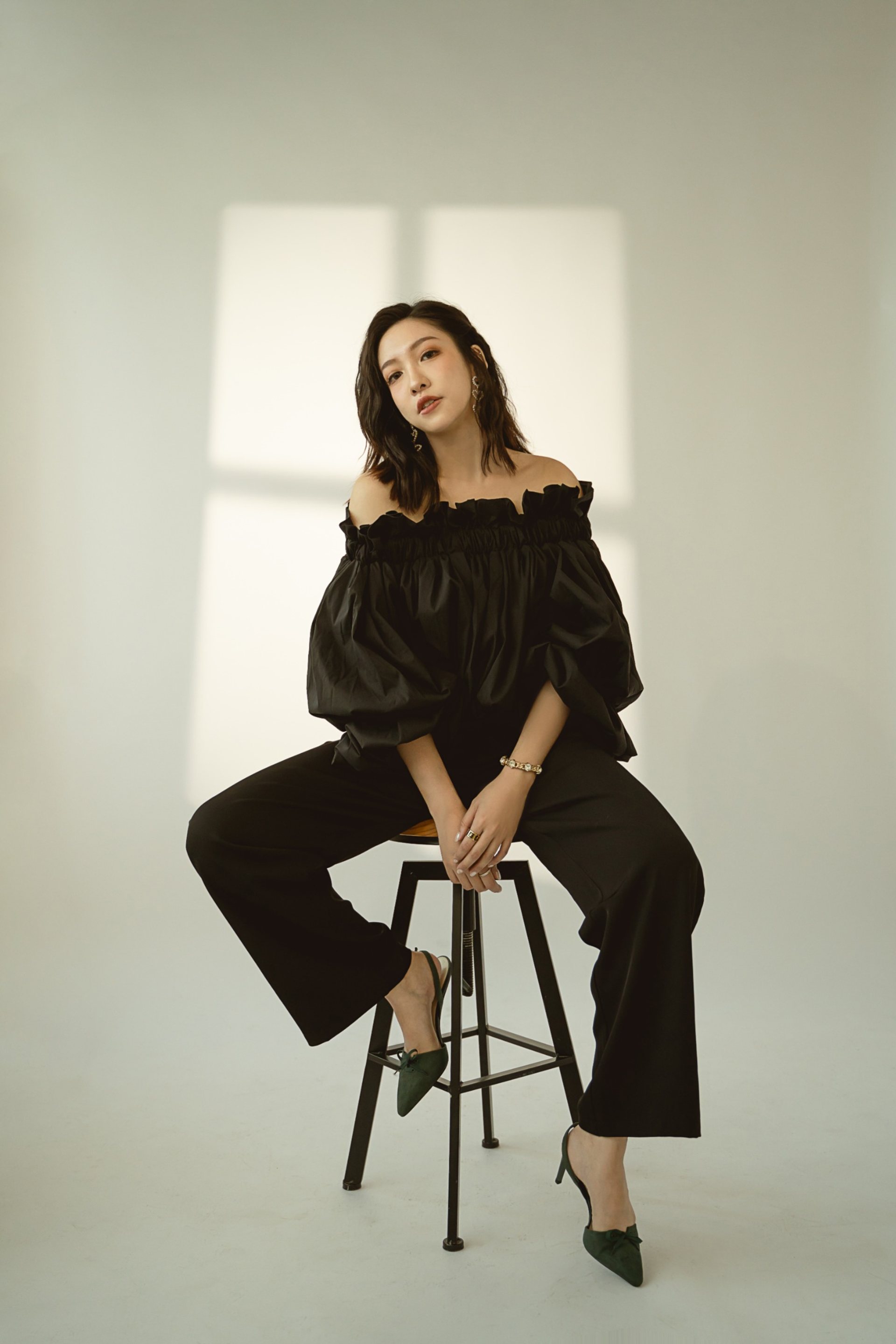 Model卡寫真－黑色澎袖上衣女性坐高腳凳米色背景