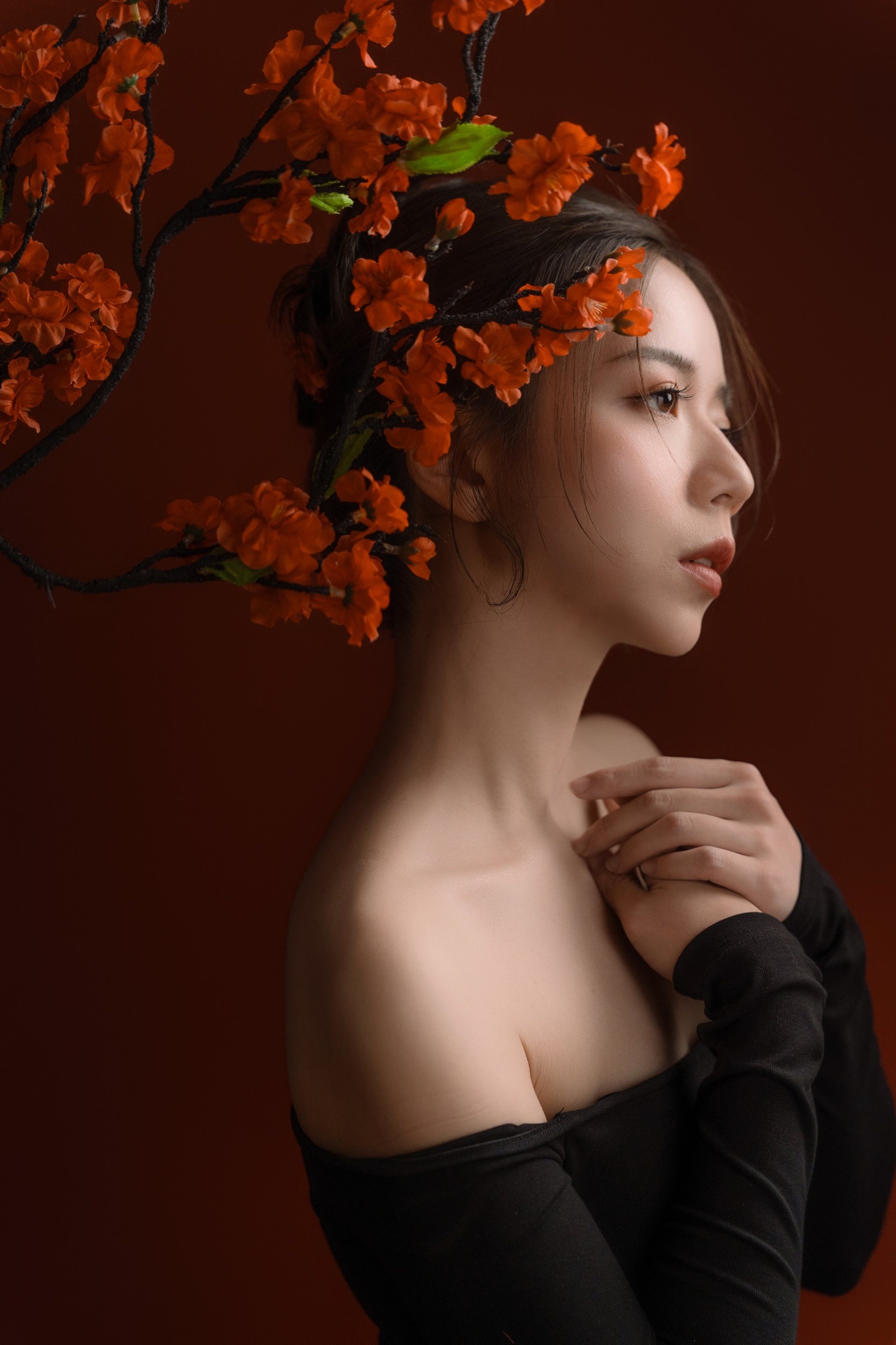 新中式主題寫真－橘紅花枝下黑衣女性側顏暗紅背景