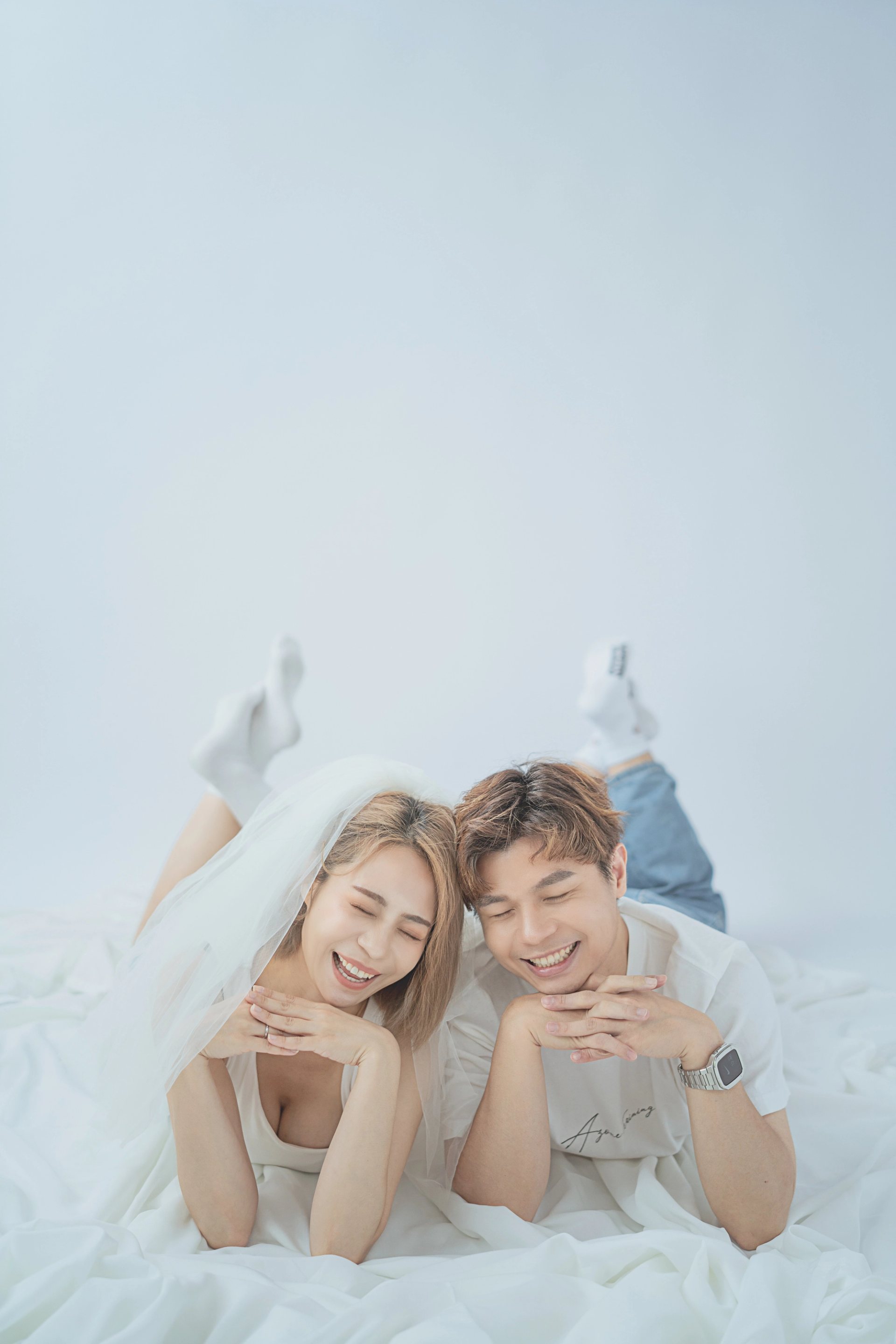 情侶輕婚紗－情侶頭紗趴臥白色布景相視而笑