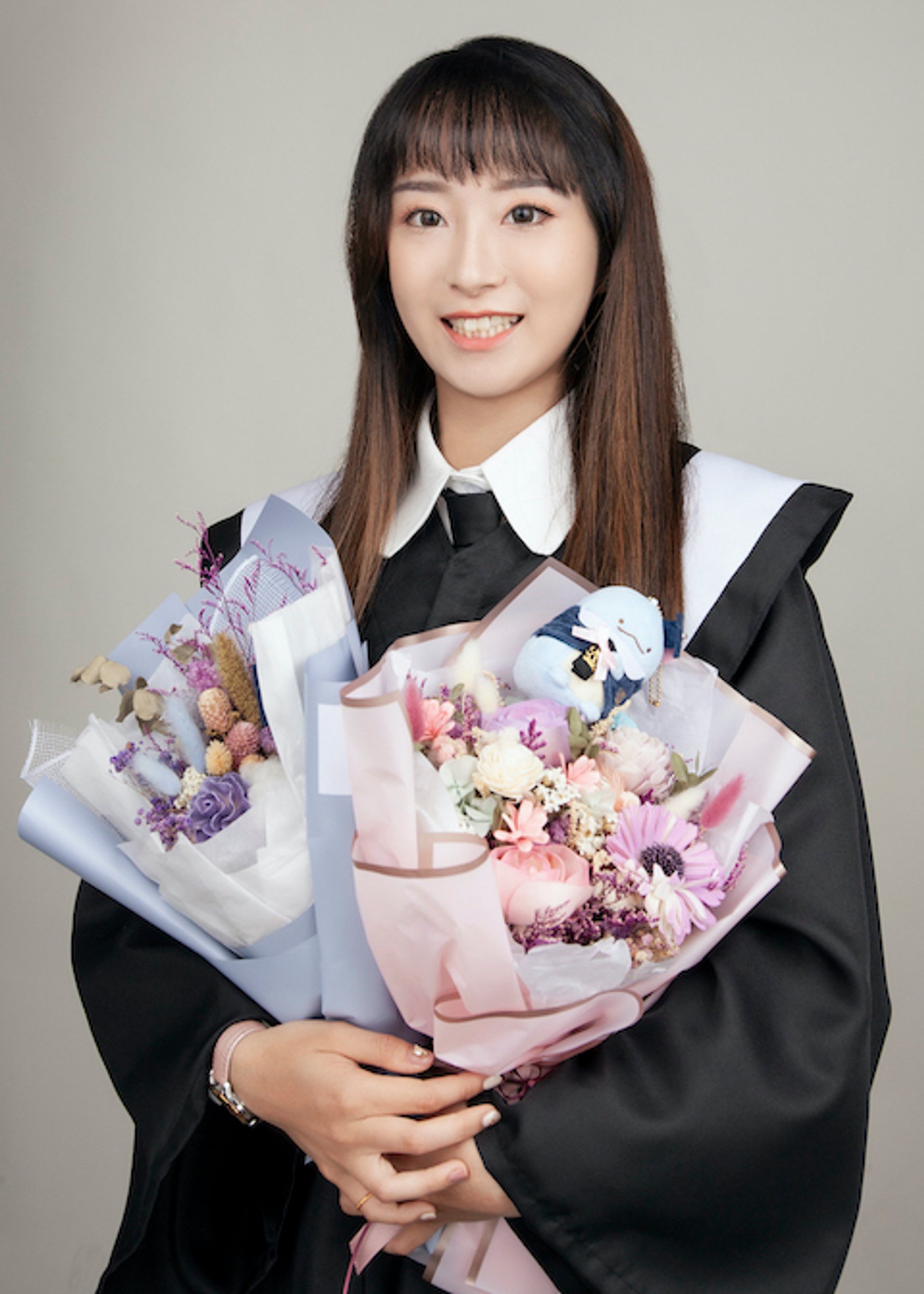 畢業寫真－女性捧兩束乾燥花束學士服灰色背景