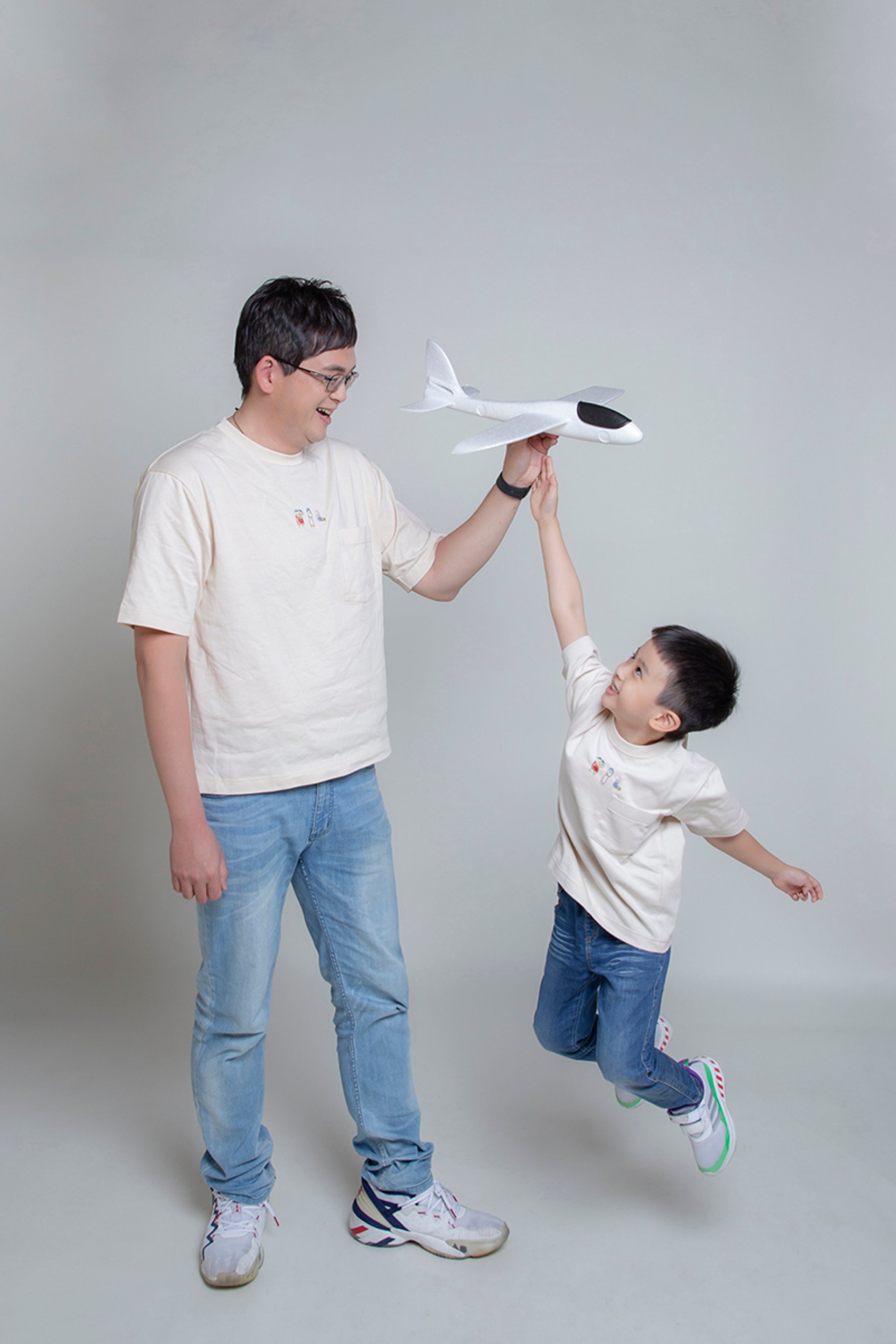 親子寫真－灰色背景父子與紙飛機跳躍合影