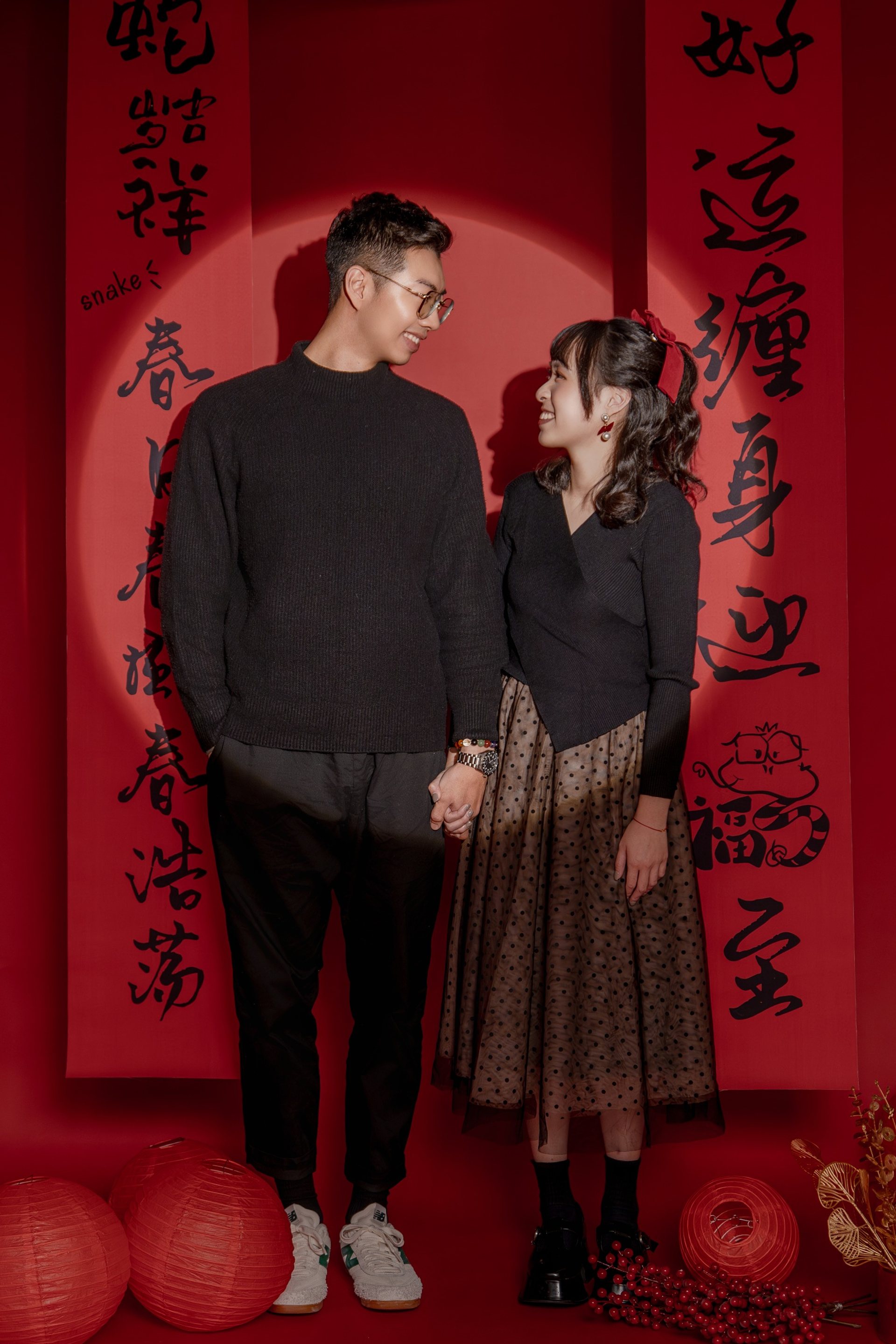 全家福多人寫真－春聯紅色佈景黑衣情侶牽手對望
