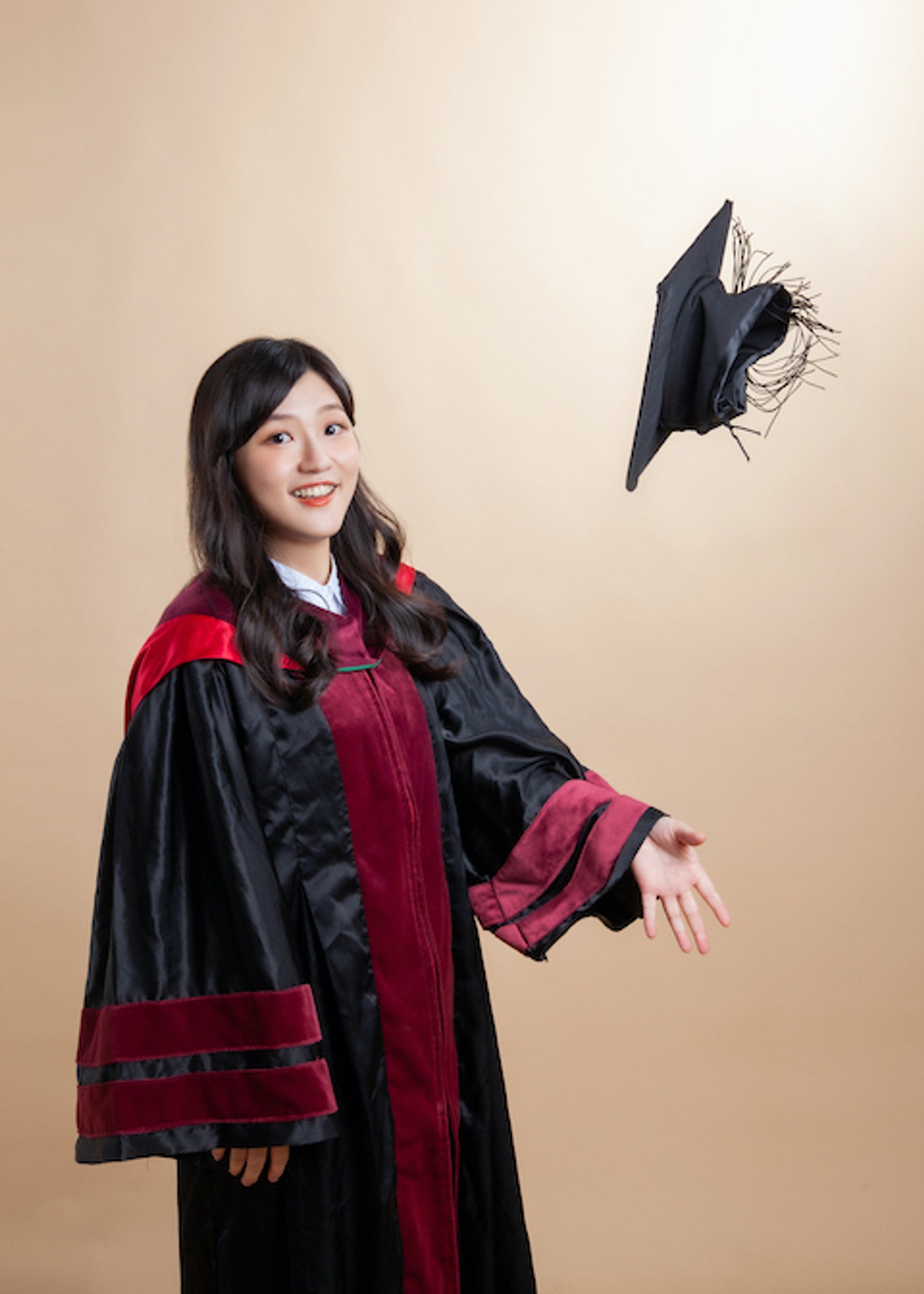 畢業寫真－女性拋學士帽瞬間酒紅黑學士服米色背景