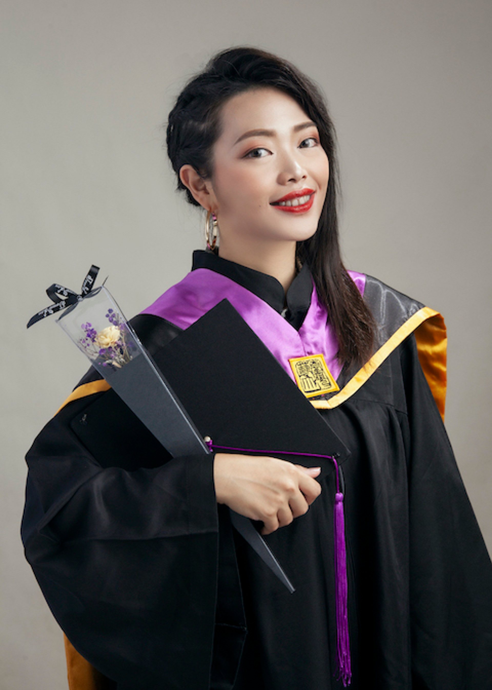 畢業寫真－紫色披肩盤髮女性持學士帽與乾燥花
