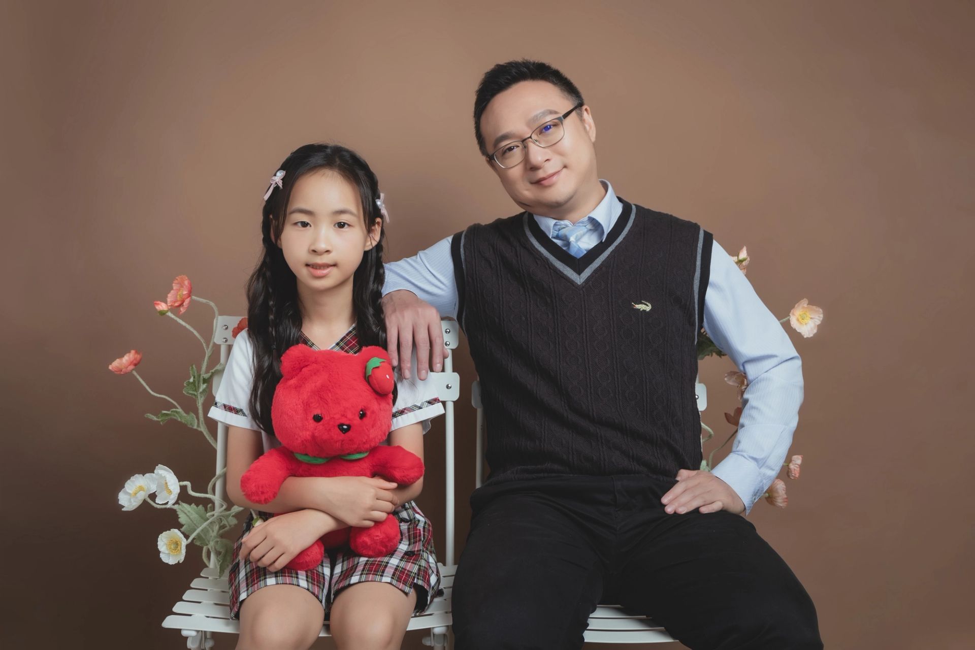 親子寫真－棕色背景父親與女兒抱著紅色小熊坐姿合影