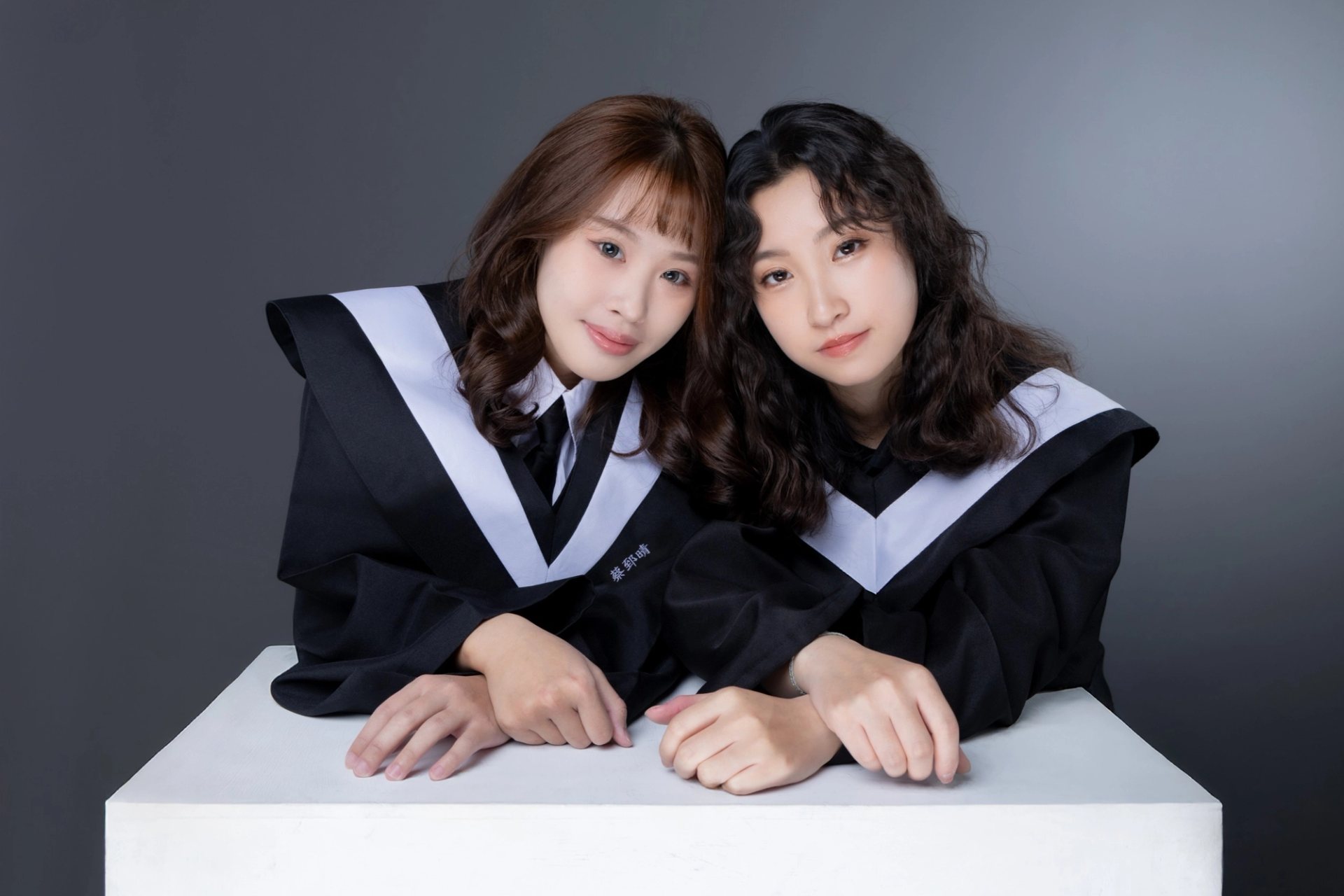 閨蜜寫真－兩位學士服女性倚白色平台灰色背景