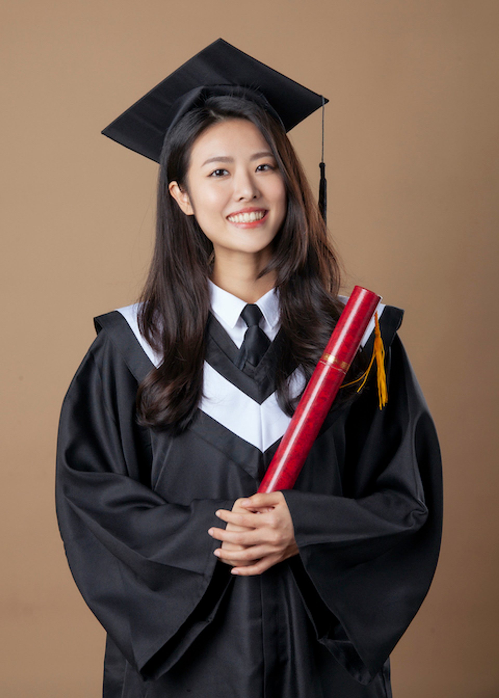 畢業寫真－學士帽女性手持紅色證書筒棕色背景