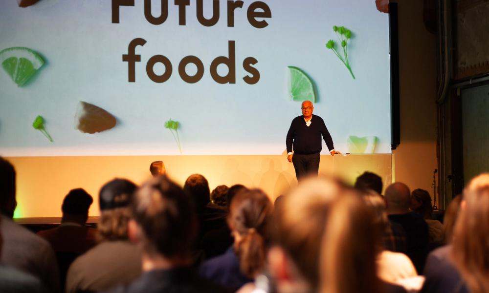 Bilde av publikum som ser på en scene med foredragsholder