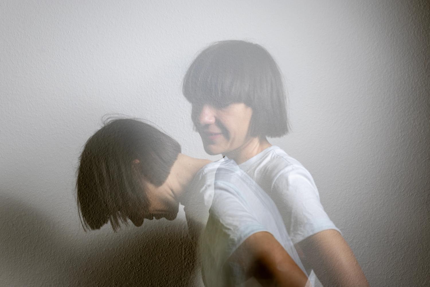 Eine weiblich gelesene Person mit dunklen kürzeren Haaren und weissem Oberteil, Sie ist zweimal abgebildet und so wird eine Bewegung angedeutet.