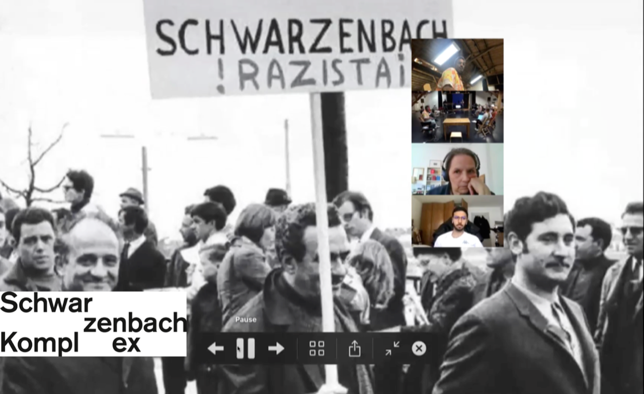 Ein Videostill, darauf ist im Hintergrund eine schwarzweiss Aufnahme zu sehen. Im Vordergrund sind untereinander vier Video-Stills, vermutlich aus einer Zoom-Konferenz oder so. Unten links steht schwarz auf weiss: Schwarzenbach Komplex.