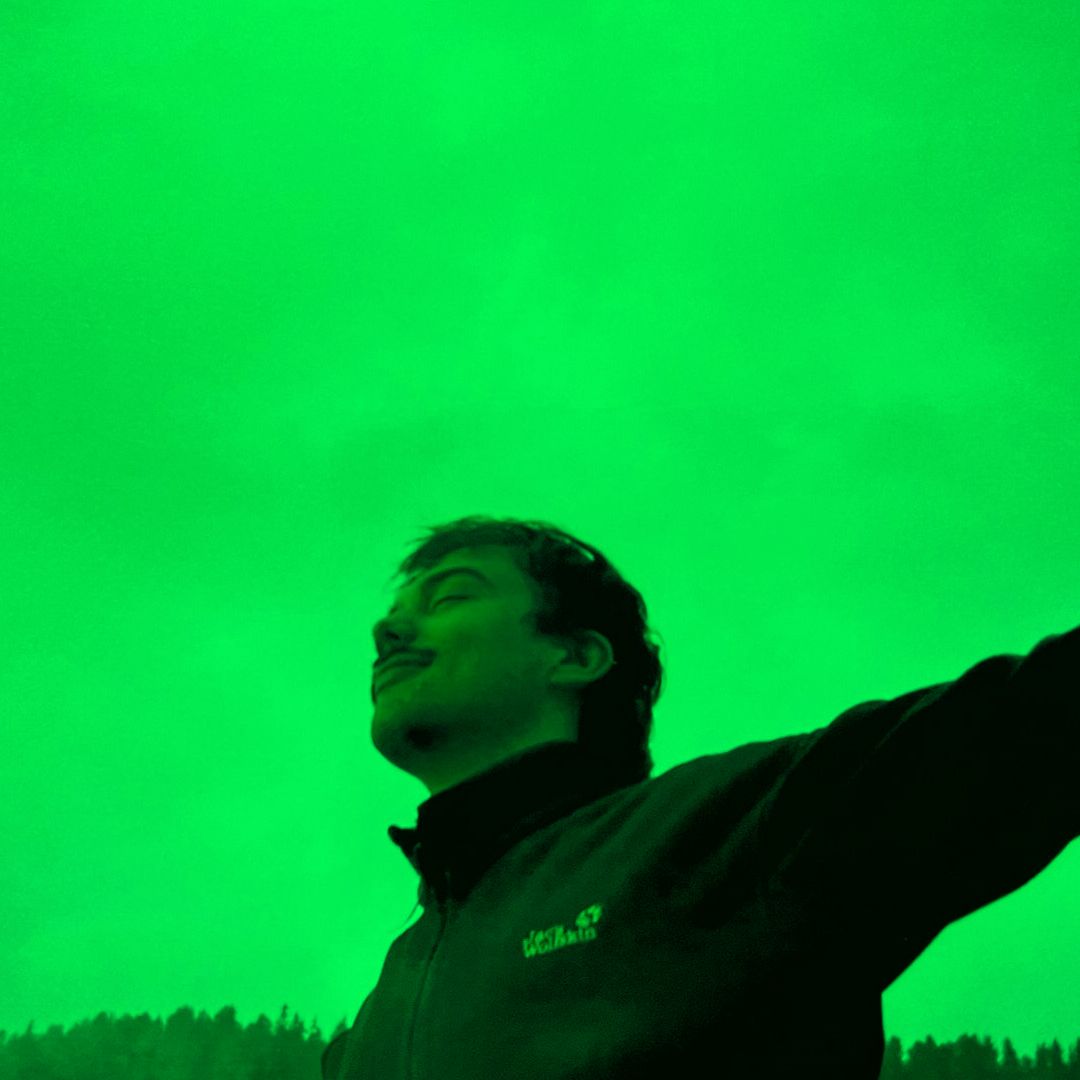 Eine schwarz-weiss Fotografie einer Person mit geschlossenen Augen vor grünem Hintergrund. 