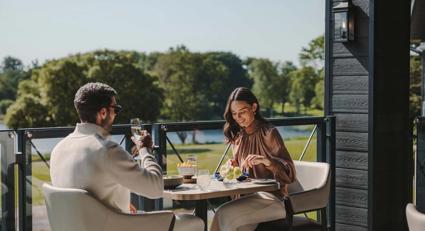 A couple dining on The Club Lounge's terrace overlooking the lake