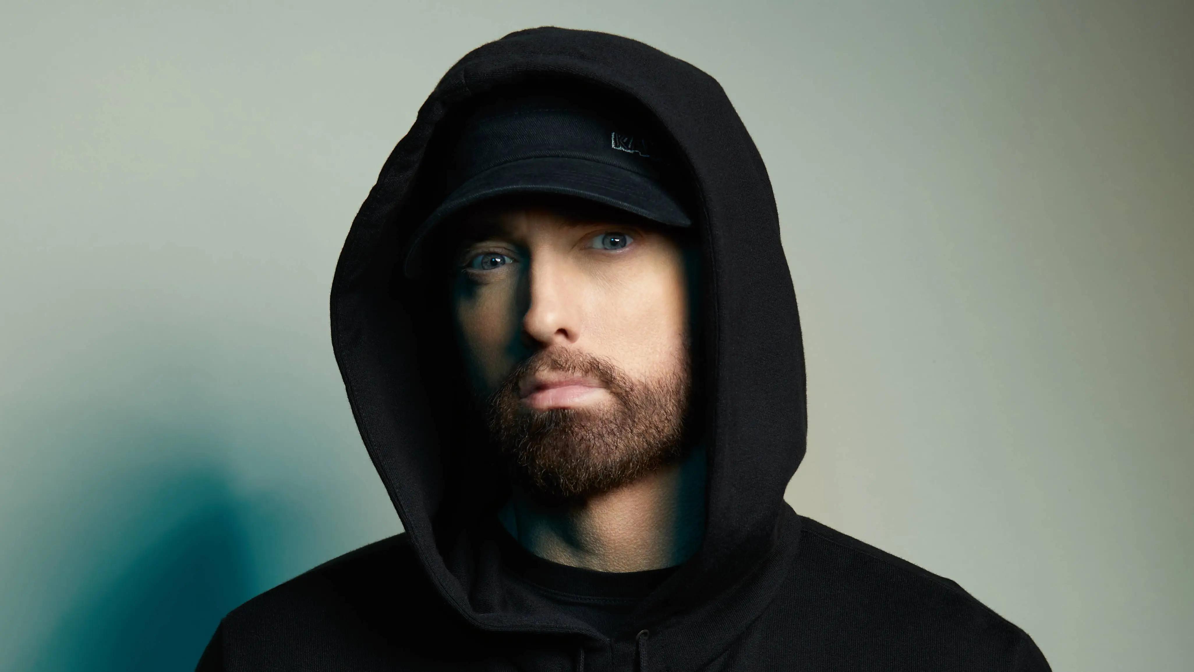 Eminem wearing a black hat and hoodie