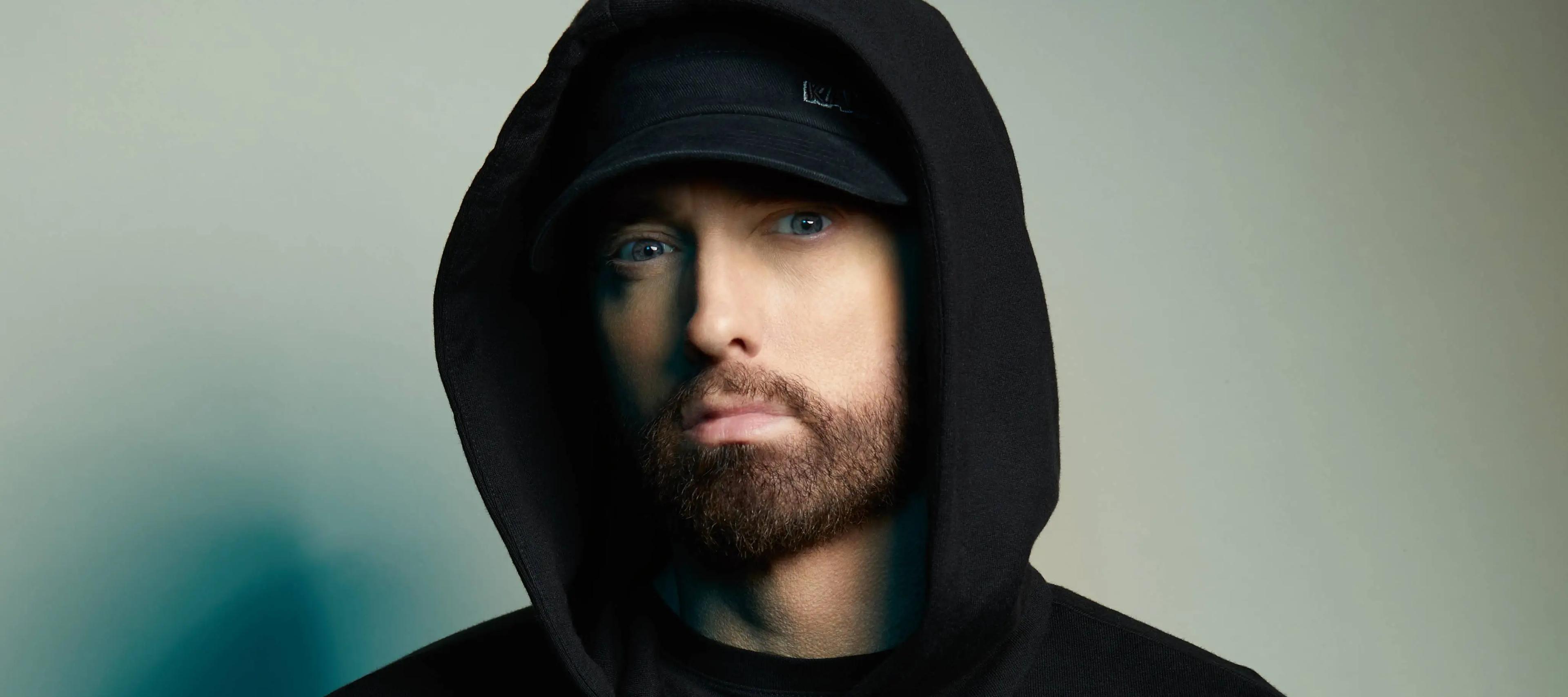 Eminem wearing a black hat and hoodie