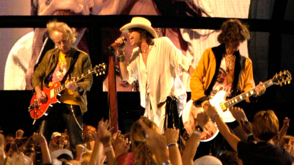 Members of Aerosmith performing on stage with guitars and microphone