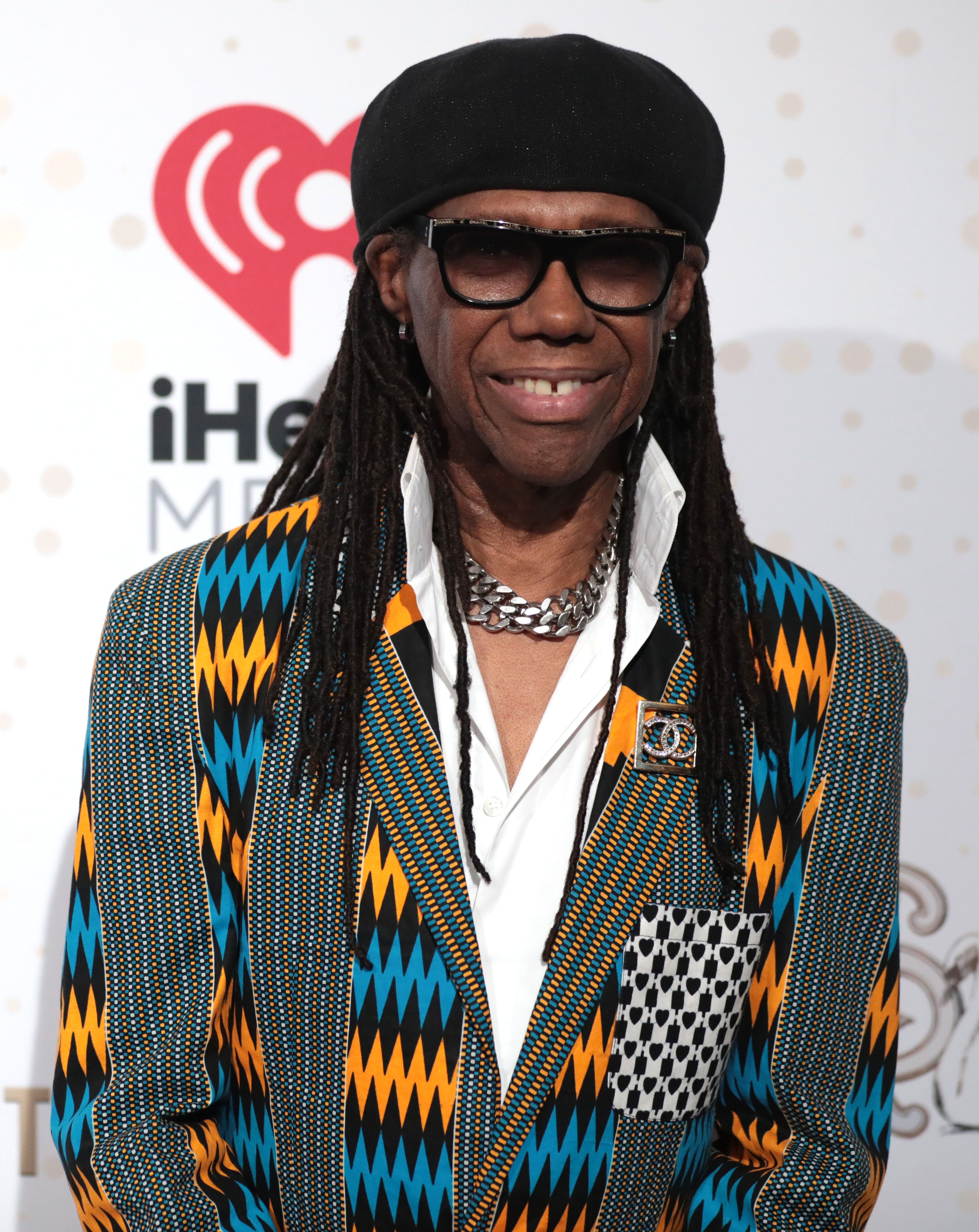 Nile Rodgers smiling at a public event, wearing sunglasses on his head.