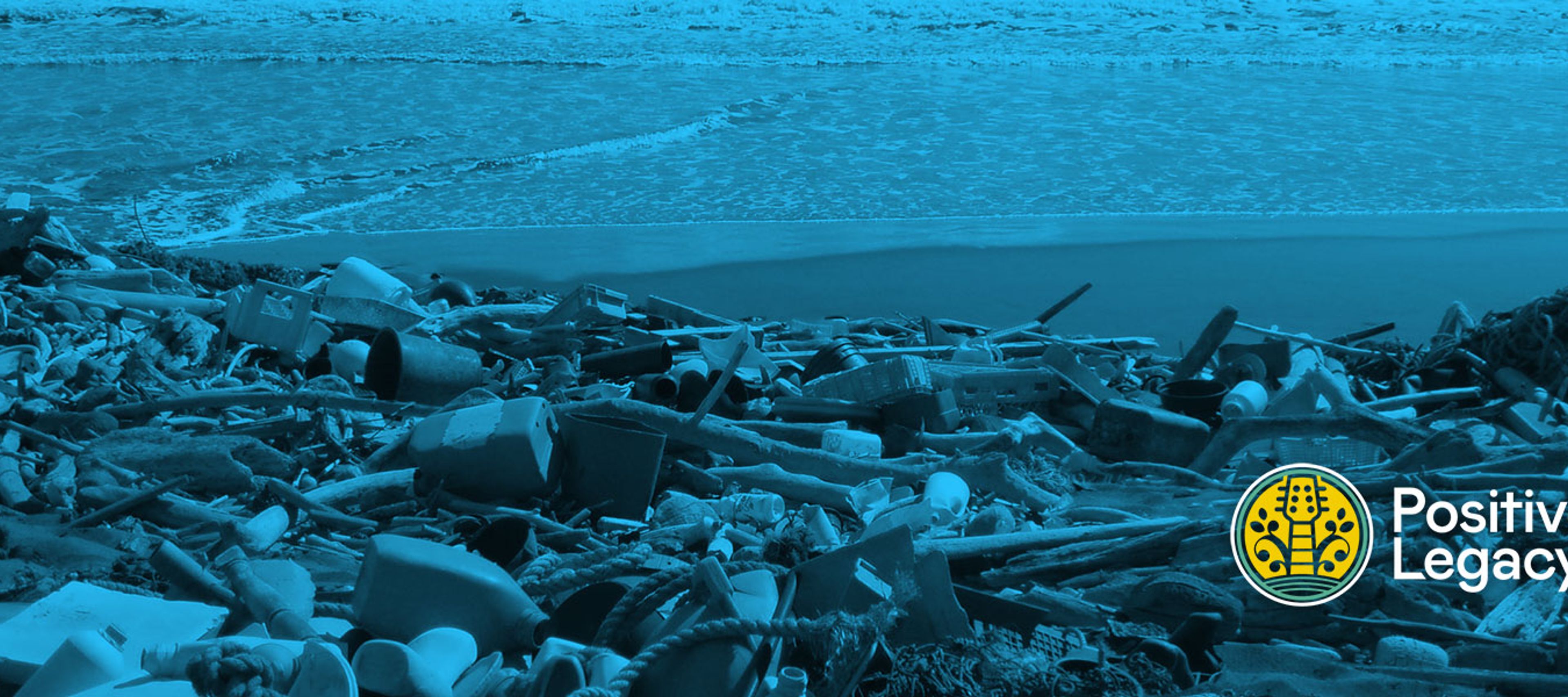 A wide, landscape-oriented image with a heavy blue tint, showing a beach covered in a significant amount of plastic pollution and debris.