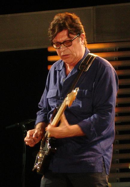 Robbie Robertson performing on stage with a guitar in 2007.