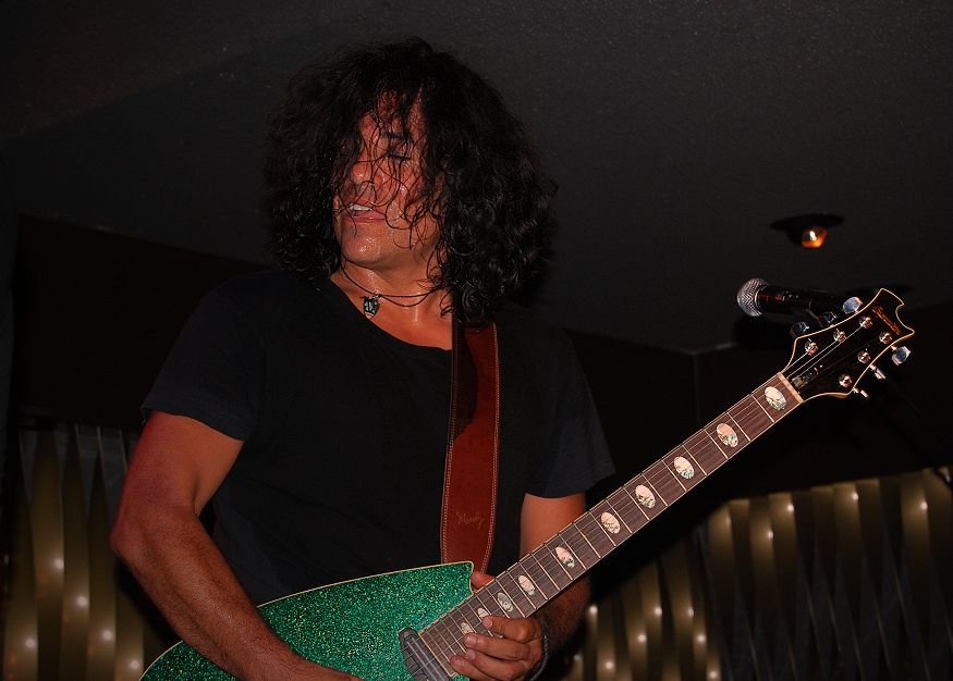 Guitarist Stevie Salas performing live on stage with a guitar.