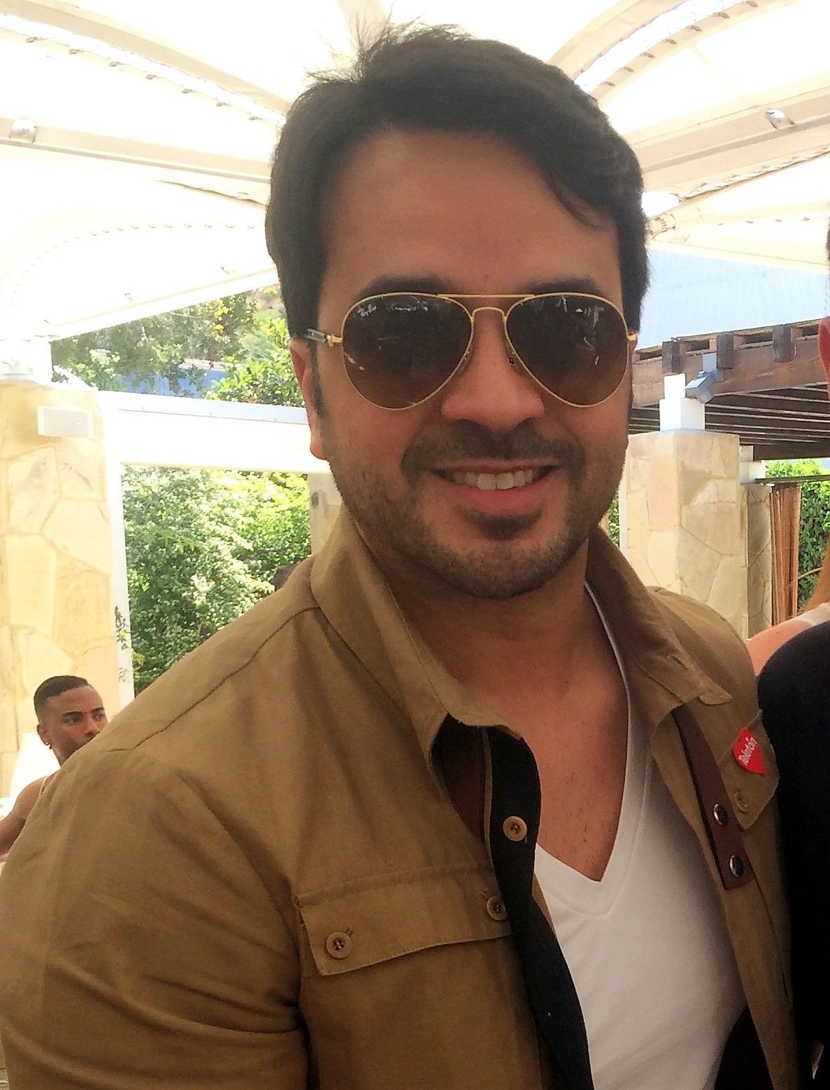 Luis Fonsi wearing sunglasses and a V-neck shirt at a public event