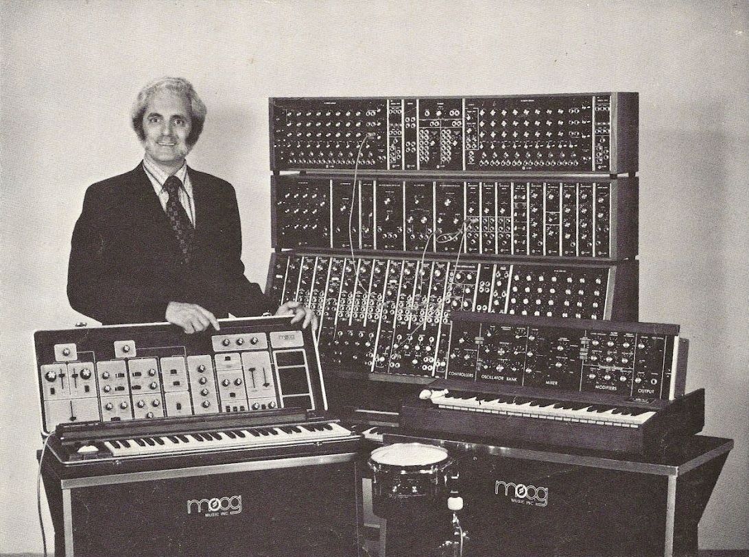 Robert Moog standing next to a row of his synthesizer instruments.