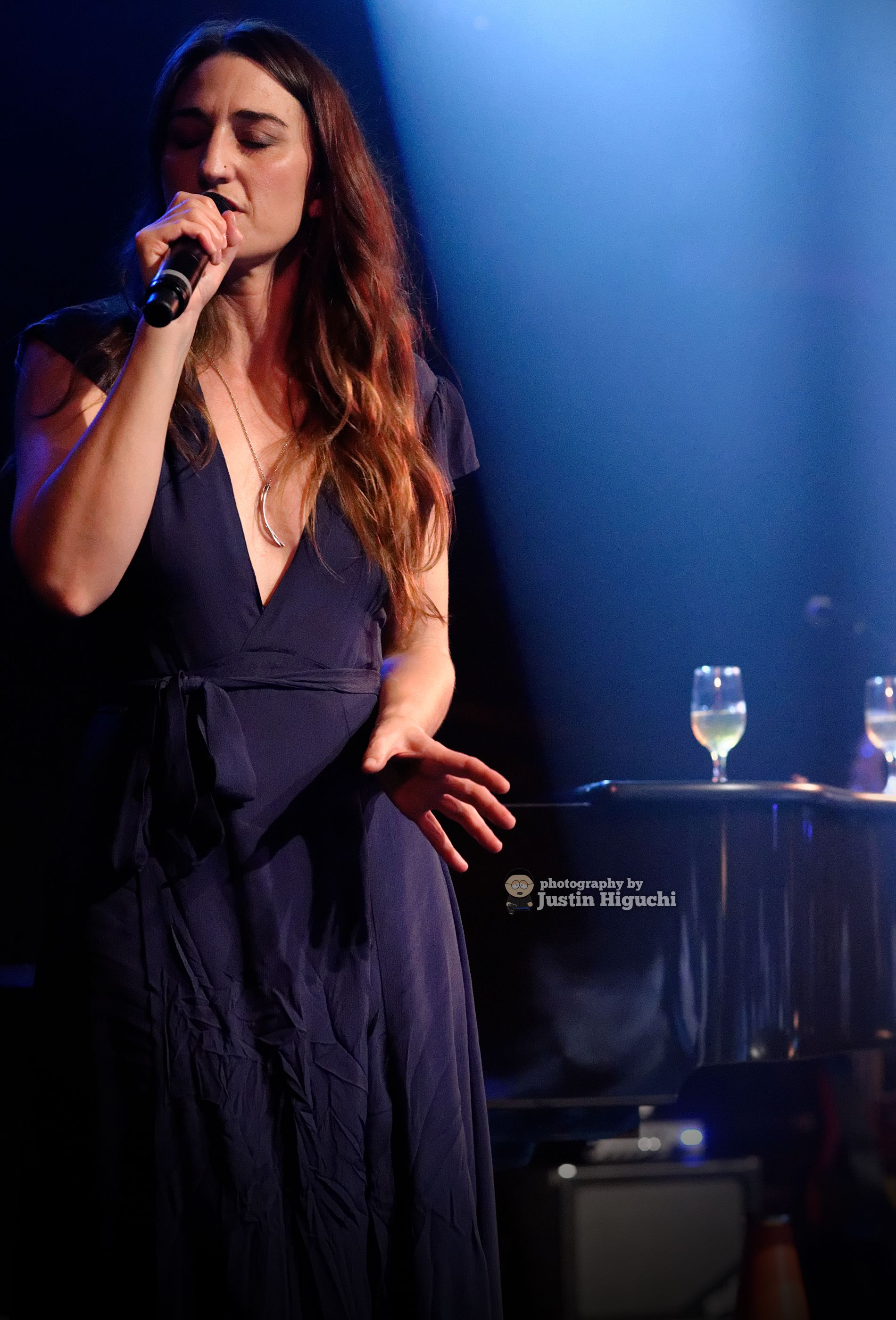 Sara Bareilles sings into a microphone with eyes closed