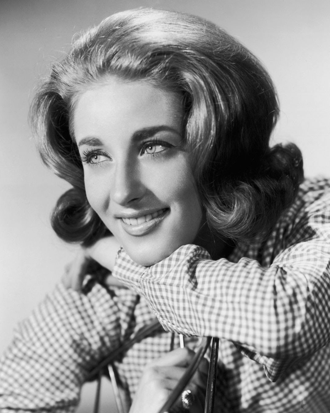 Lesley Gore smiling in a 1963 publicity photo, arms resting on the back of a chair