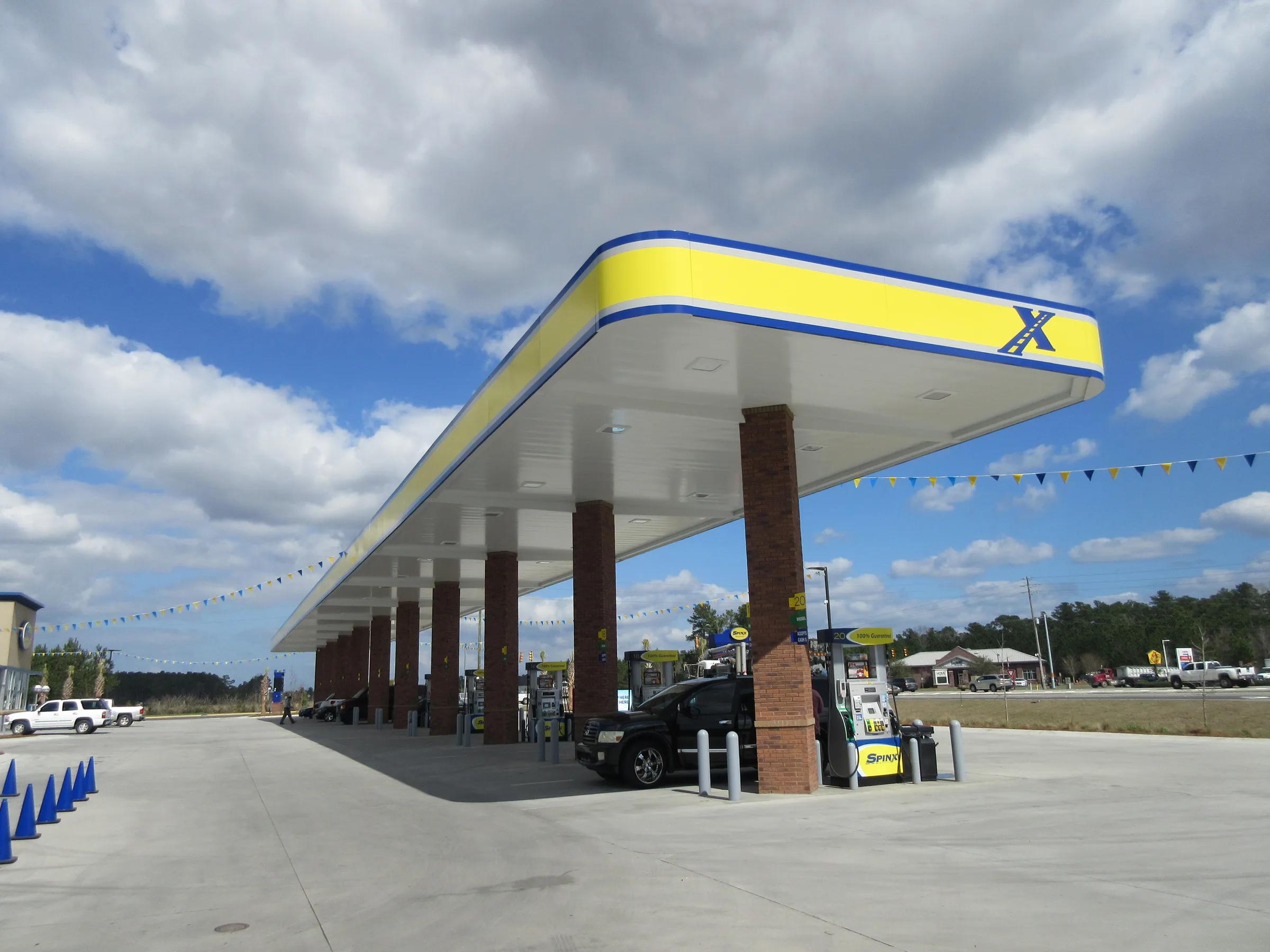 Long canopy with a yellow and blue fascia on brick columns, pennants strung overhead