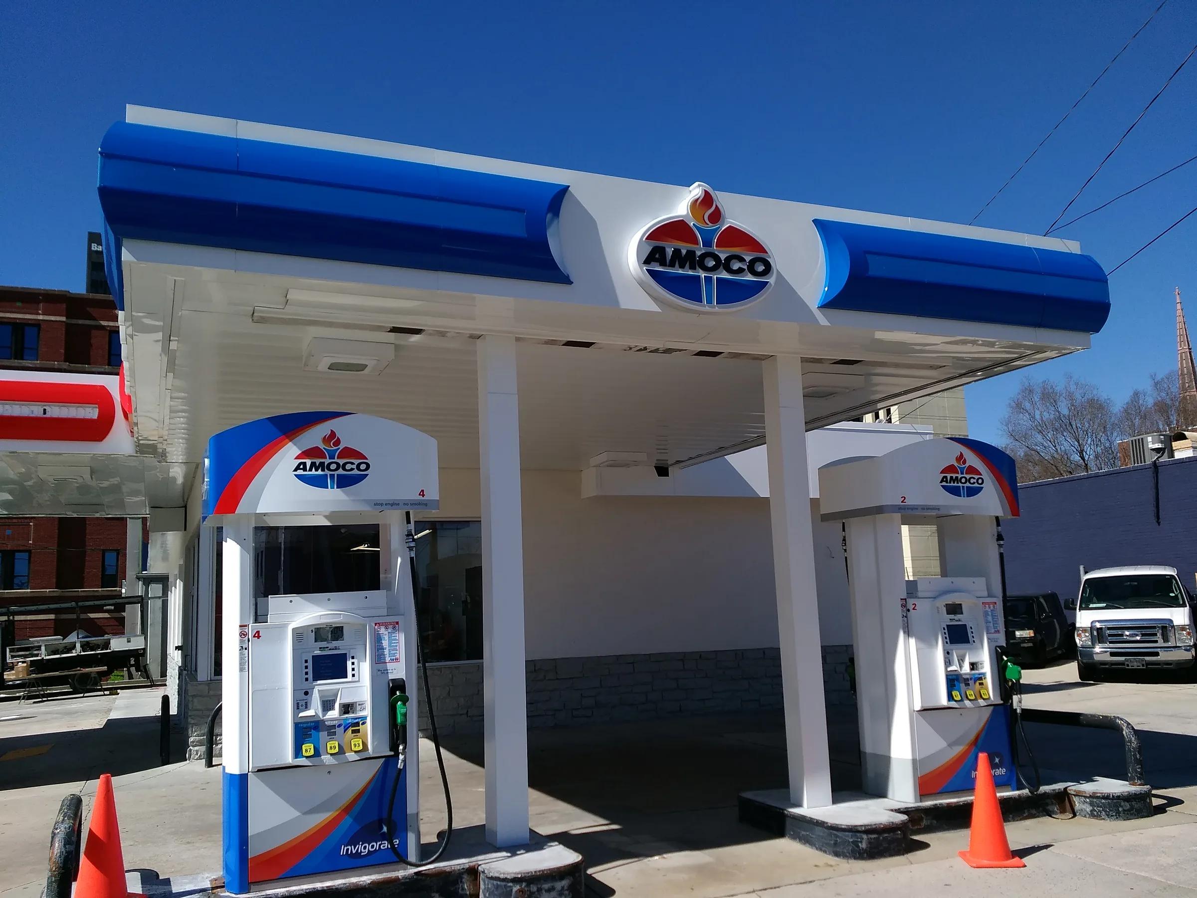Close view of an Amoco canopy fascia and logo sign over two dispensers, safety cones on the island