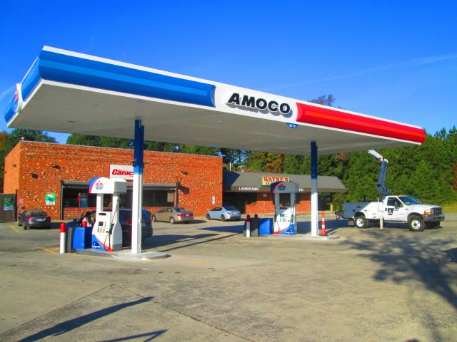 Amoco canopy with a blue, white and red fascia over two dispensers, a bucket truck parked alongside