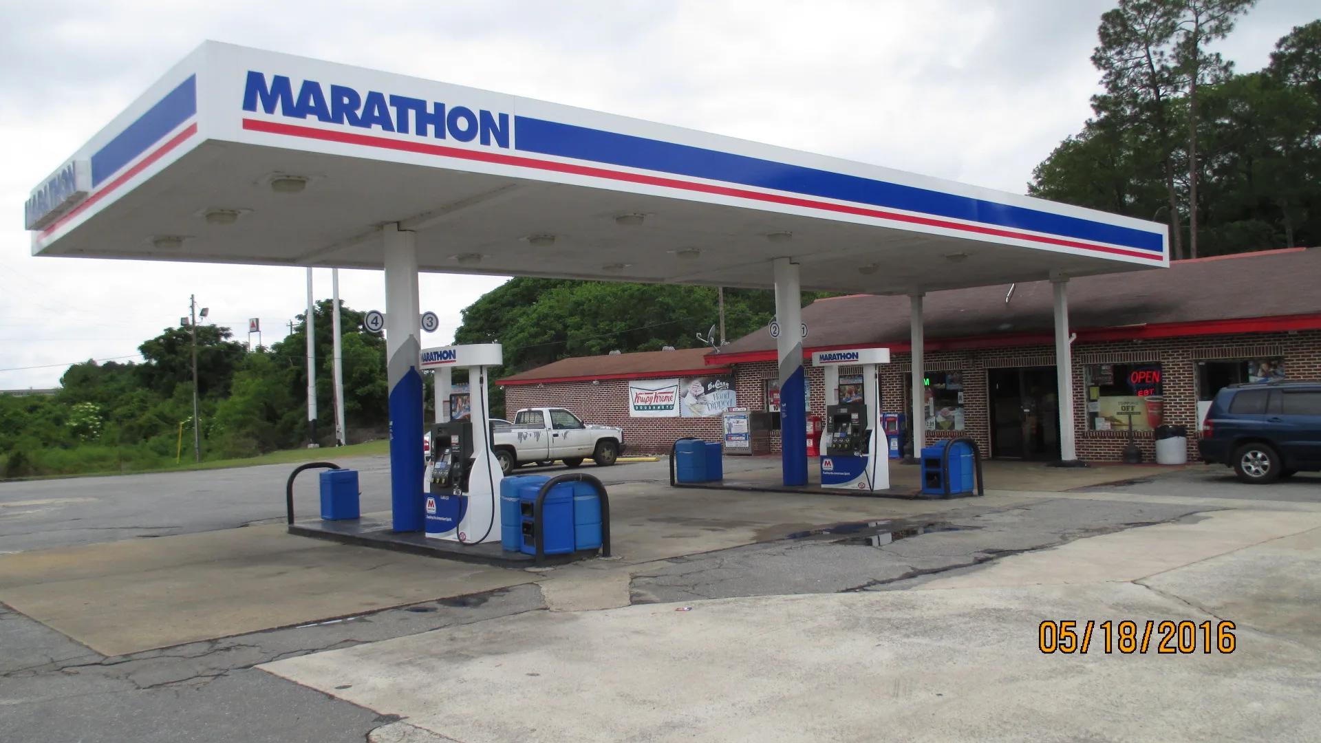 Marathon canopy with a blue and red striped fascia over dispensers, a store behind