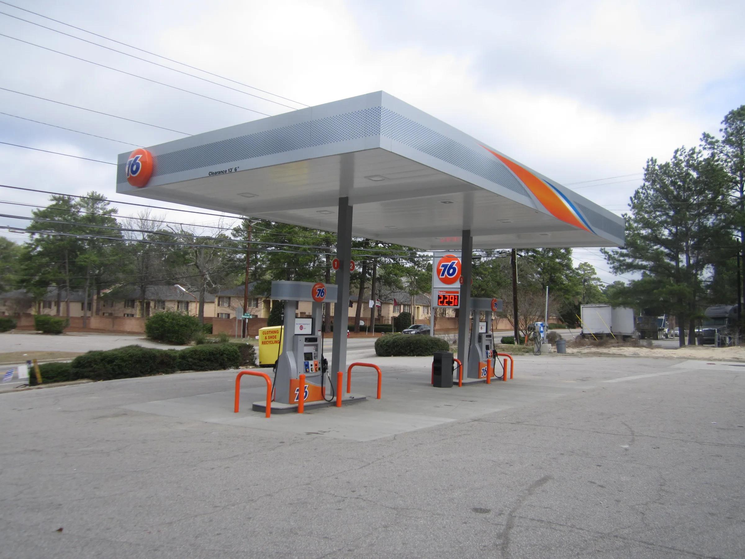 76 canopy with a grey, orange and blue fascia over dispensers with orange bollards
