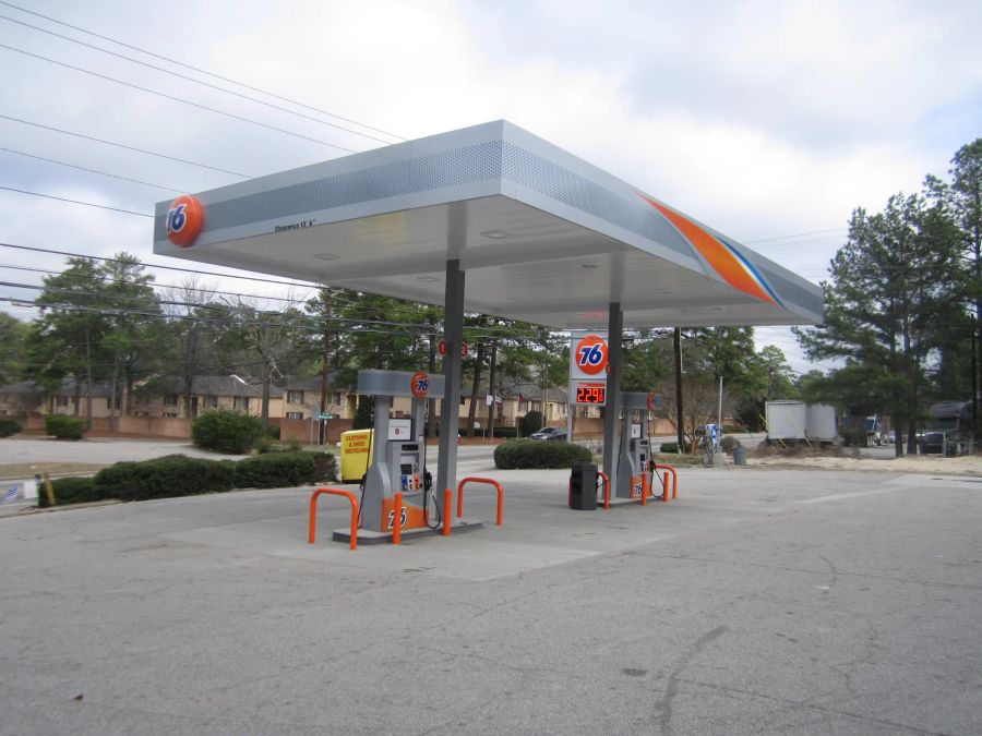 76 canopy with a grey, orange and blue fascia over dispensers with orange bollards