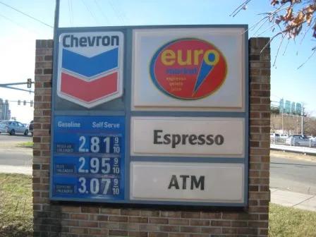 Chevron price sign on a brick monument base, beside panels for a market, espresso and an ATM