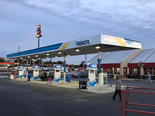 Valero canopy at dusk with lit dispensers in front of a convenience store